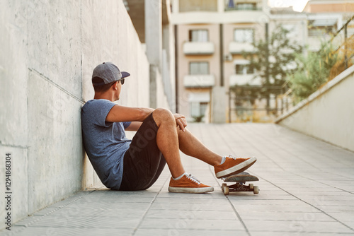 Skateboarder relaxing after practicing in urban environment