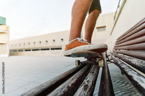 Unrecognizable skateboarder balancing on bench in urban setting