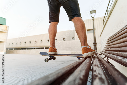 Unrecognizable skateboarder balancing on bench in urban setting