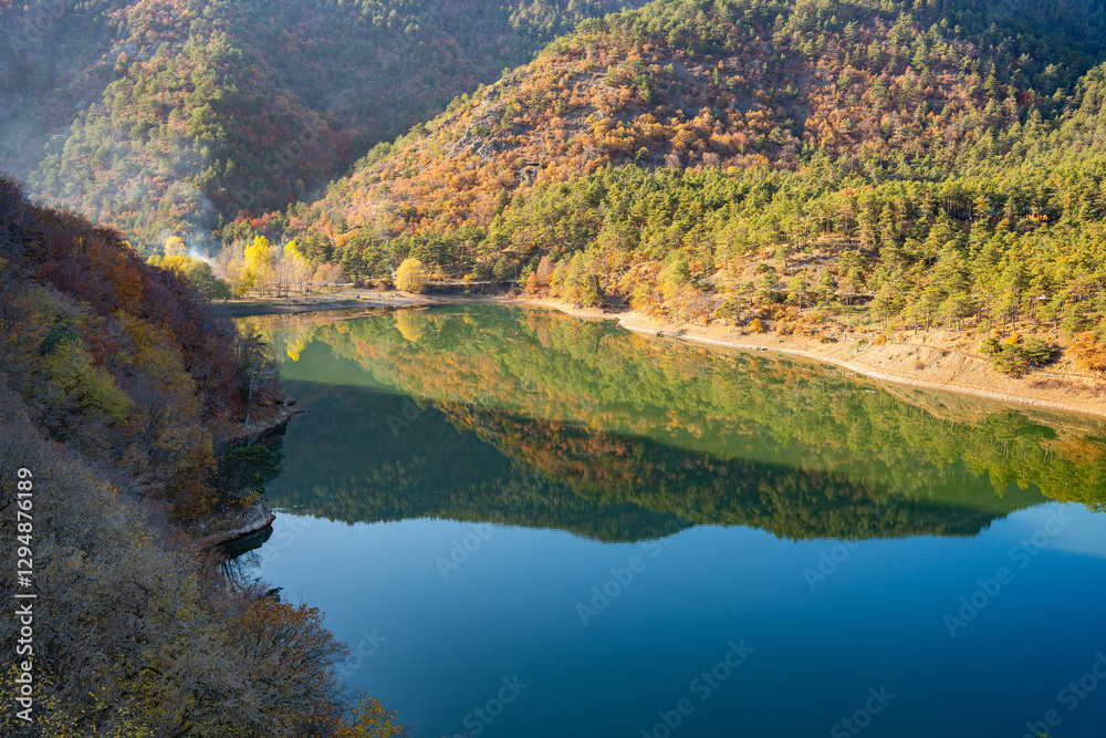 Fototapeta premium Autumn reflections landscape on calm waters of Boraboy Lake Nature Park. Scenic forest hills and tranquil lake in fall. Peaceful scene with trees and blue sky background. Seasonal change