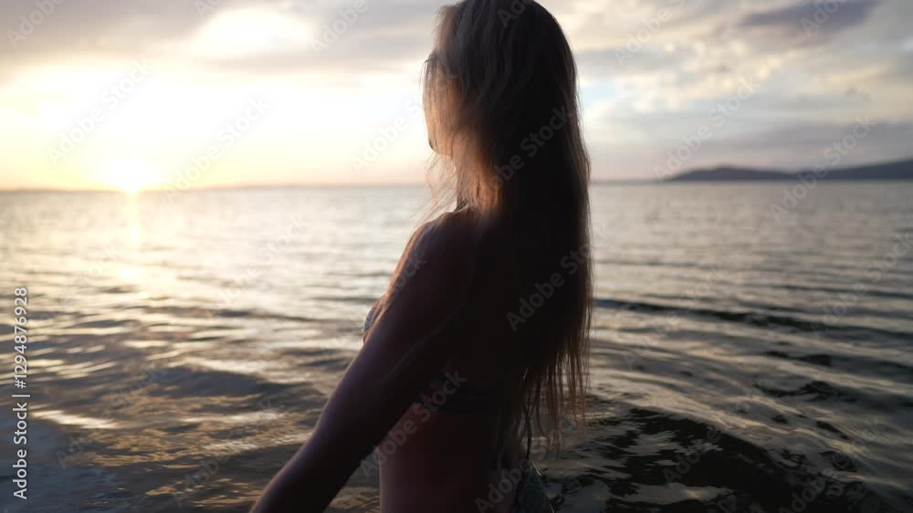 A middle-aged woman stands in the gentle waves of a lake, smiling as she enjoys a warm summer evening, embracing the beauty of nature and freedom. A middle-aged woman stands in the gentle waves of a lake, smiling as she enjoys a warm summer evening, embracing the beauty of nature and freedom.