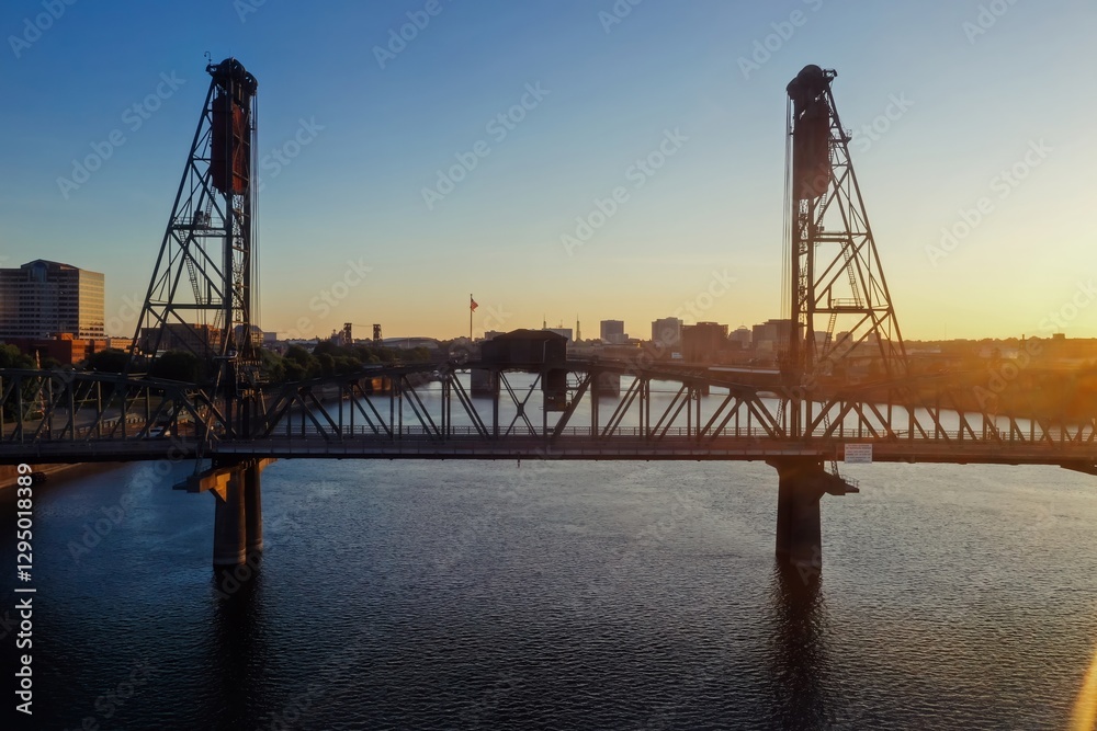 Fototapeta premium Sunrise over the Willamette River and the iconic Hawthorne Bridge in Portland, Oregon. Steel structure, calm water, city skyline. Portland, Oregon, USA
