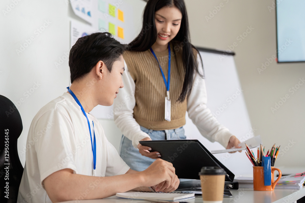 Fototapeta premium Young professionals discussing financial strategies over documents in a modern office setting.