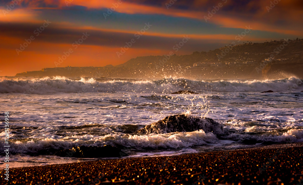 Close-up of sea splash along the shoreline of Palos Verdes Estates, CA with a background of dramatic pink and blue sky and mountain landscape