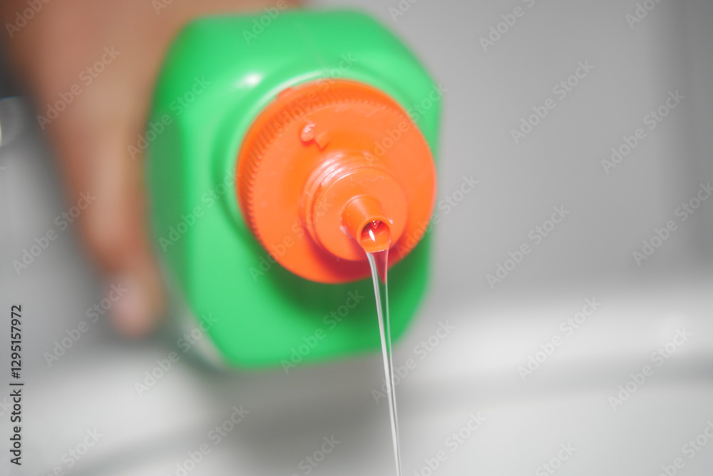 Pouring liquid from a green bottle in a bathroom setting Pouring liquid from a green bottle in a bathroom setting