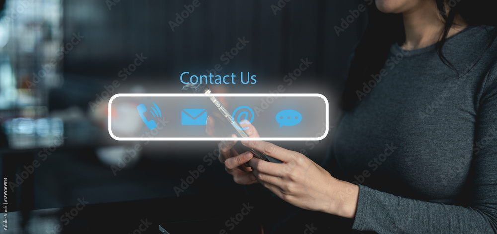 A person holds a smartphone displaying contact options, including phone, email, and social media icons, in a dimly lit setting. A person holds a smartphone displaying contact options, including phone, email, and social media icons, in a dimly lit setting.
