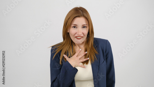 In a studio setting, a young businesswoman wearing a suit is standing in front of a white background, gagging as if feeling nauseous and looking at the camera