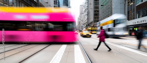 Blurred pink tram and pedestrian in city street.