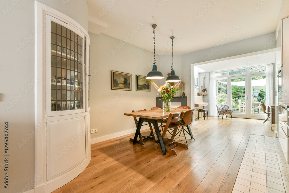 Fototapeta premium Stylish dining area featuring a wooden table, contemporary chairs, and large windows for ample natural light, creating a warm atmosphere.