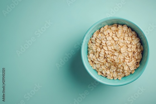 A teal bowl brimful of rolled oats sits against a mint background. Perfect for healthy eating, breakfast, or diet content.