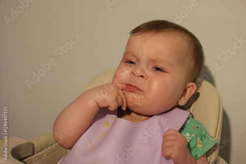 Adorable 6-Month-Old Baby Girl with Blue Eyes Eating Messy Baby Food
