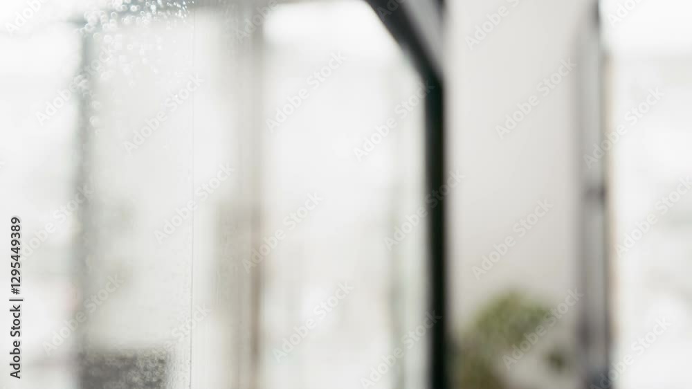 Close up shot of hand of unrecognizable staff washing glass surface with detergent and squeegee indoors Close up shot of hand of unrecognizable staff washing glass surface with detergent and squeegee indoors