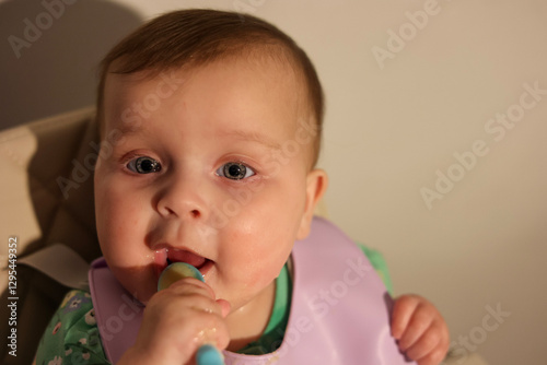 Adorable 6-Month-Old Baby Girl with Blue Eyes Eating Messy Baby Food
