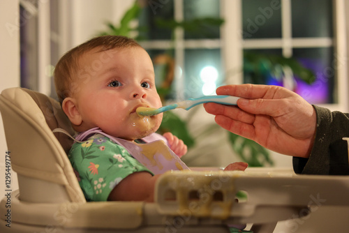 Adorable 6-Month-Old Baby Girl with Blue Eyes Eating Messy Baby Food
