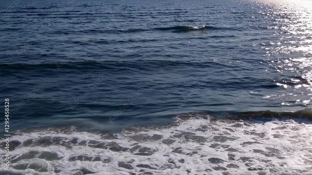 Aerial video captures gentle ocean waves lapping onto a sandy shore, showcasing a serene and tranquil seascape from a high angle view. Aerial video captures gentle ocean waves lapping onto a sandy shore, showcasing a serene and tranquil seascape from a high angle view.