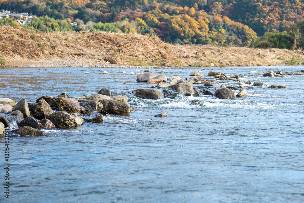 Scenic Hozugawa River with rocks and autumn foliage backdrop