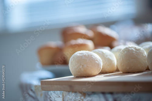 Wallpaper Mural Soft dough balls rest on a wooden board, ready for baking, with golden brown muffins in the blurred background. Torontodigital.ca