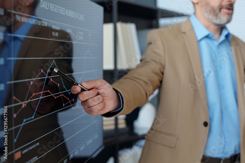 Close up of unrecognizable businessman holding pen and pointing at statistical data graph on digital board during meeting in office copy space