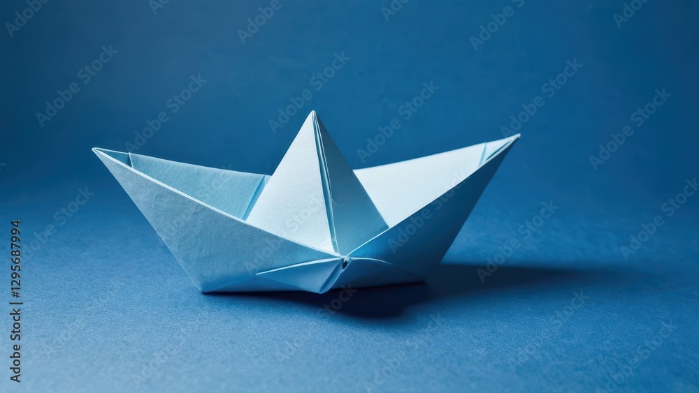Obraz premium a delicate blue origami boat rests peacefully on a solid blue surface
