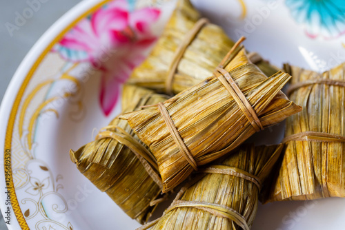 Thai coconut sticky rice and banana wrapped with Nipa palm leaves (commonly with banana leaves), placing in Thai old style cooking plate