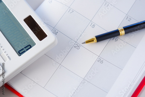 カレンダーを眺めながら電卓を叩いて、給料日の25日を待ち望んでいるイメージ
