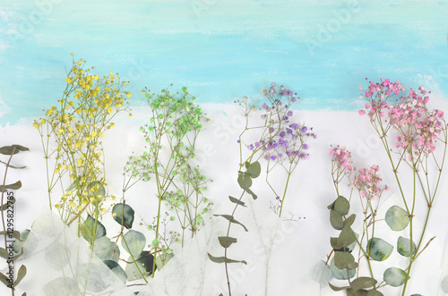Obraz na płótnie Spring flowers (gypsophila) and eucalyptus on blue, painted background with empty space to fill with content above. w salonie