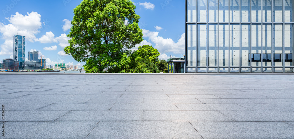 Empty square floor and modern glass wall building with green trees in city park