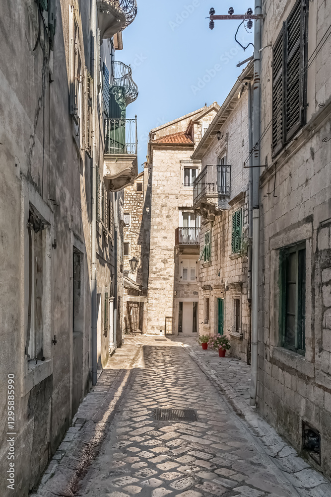 Peaceful, sunlit alleyway in the historic town of Kotor, Montenegro. Traditional stone buildings with charming balconies and colorful flower pots, reflecting the quaint atmosphere of Kotor Old Town Peaceful, sunlit alleyway in the historic town of Kotor, Montenegro. Traditional stone buildings with charming balconies and colorful flower pots, reflecting the quaint atmosphere of Kotor Old Town