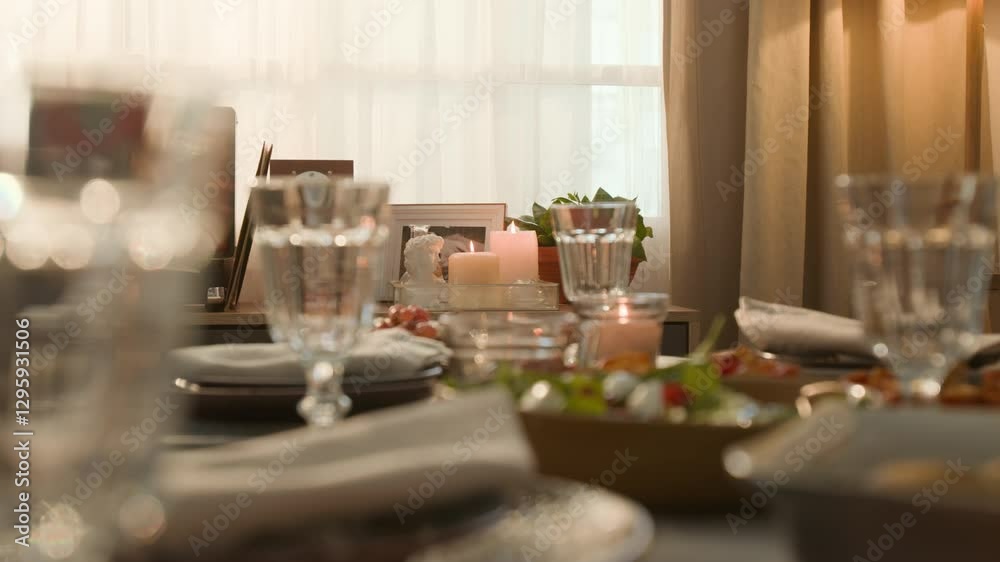 Dining table with elegant glassware and plates with napkins and subtly lit by candles, set for special occasion Dining table with elegant glassware and plates with napkins and subtly lit by candles, set for special occasion