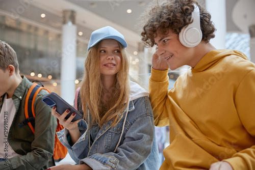 Teen boy sharing favorite music track in headphones to girl friend