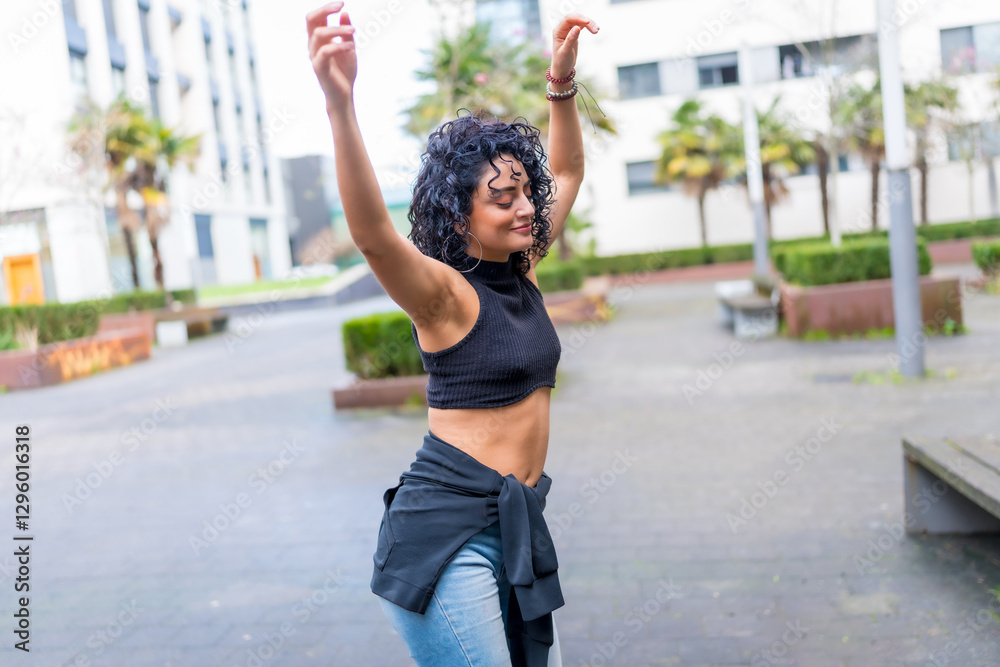 Young latin dancer is dancing in the street with arms raised Young latin dancer is dancing in the street with arms raised