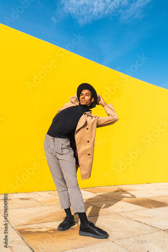Young man dancing in front of yellow wall
