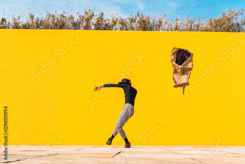 Young man dancing in front of yellow wall photo