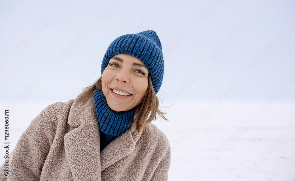 Smiling woman in winter clothes standing in a snowy field Smiling woman in winter clothes standing in a snowy field