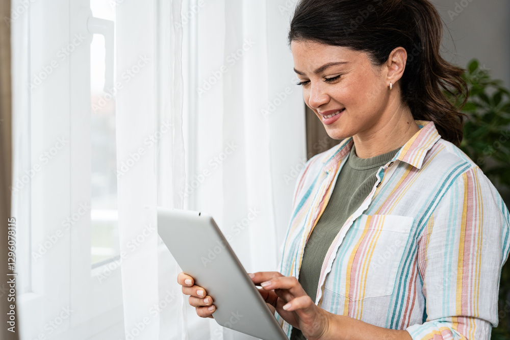 Real estate agent with tablet pc looking through window. Young business woman working at home, using device gadget. Successful professional occupation graphic designer female taking a break from work. Real estate agent with tablet pc looking through window. Young business woman working at home, using device gadget. Successful professional occupation graphic designer female taking a break from work.