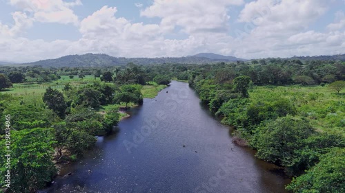 Aerial footage of scenic Rio Yuna winding through vibrant green landscapes and dense tropical vegetation in Cotuí, Sánchez Ramírez, capturing the beauty of nature, Dominican Republic photo