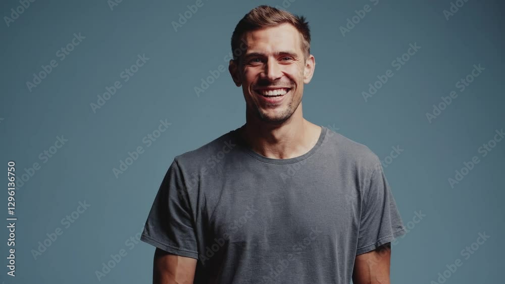 Cheerful man standing in studio, giving thumbs up with confident smile against blue background, expressing positive agreement and support Cheerful man standing in studio, giving thumbs up with confident smile against blue background, expressing positive agreement and support