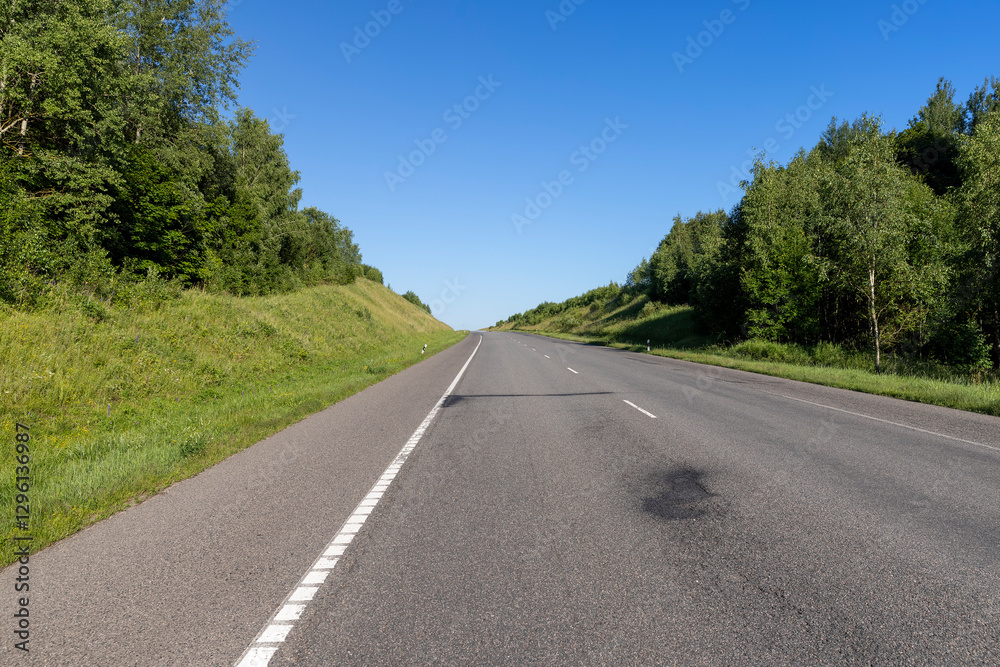 Fototapeta premium an empty straight paved road against a blue sky background