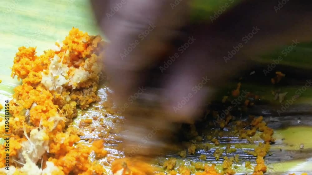 Man's hand smoothes turmeric using a grater manually