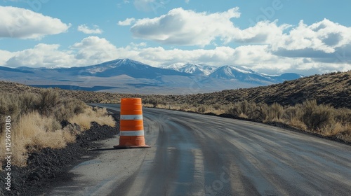 A vibrant orange construction cone, its stripes a stark contrast to the freshly paved asphalt, delineates a section of road, promising a smoother journey ahead.