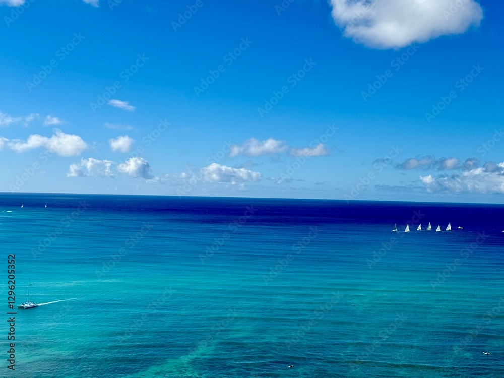 Obraz premium Wide open turquoise ocean view with small white sailboats in the background