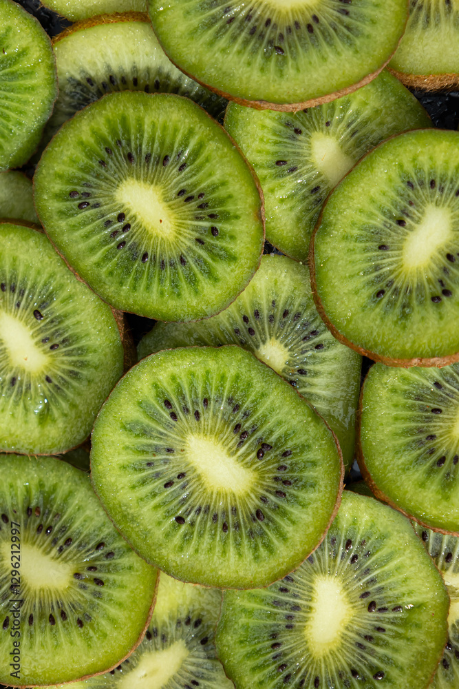 Vertical image in close up of fresh kiwis cut into slices. Greenish, ellipse shaped food covered with hairy skin Vertical image in close up of fresh kiwis cut into slices. Greenish, ellipse shaped food covered with hairy skin