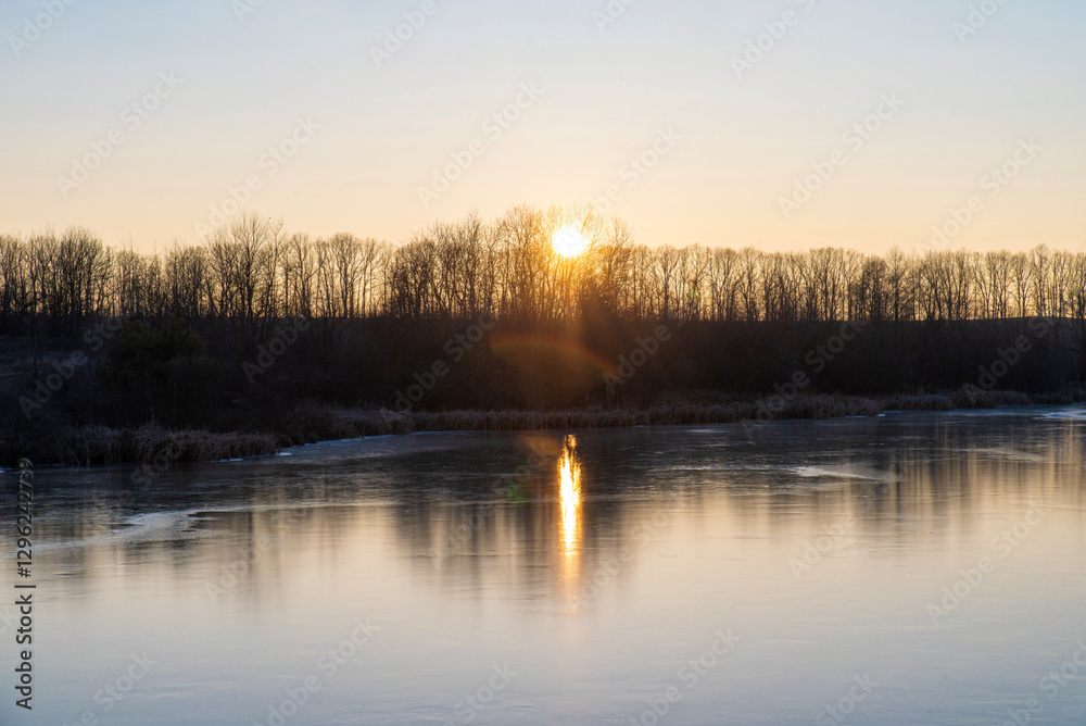 Lake with frozen water and trees at sunset Lake with frozen water and trees at sunset