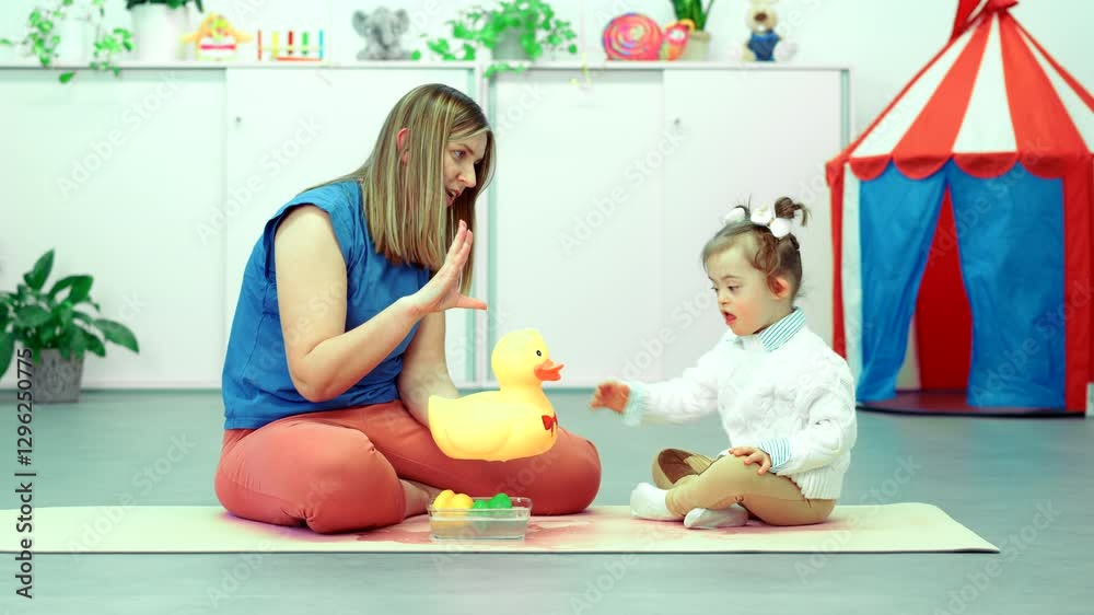 Nonverbal child with Down syndrome learning baby sign language with the help of a speech therapist. Child therapy, neurodiversity, learning difficulty, developmental disability.