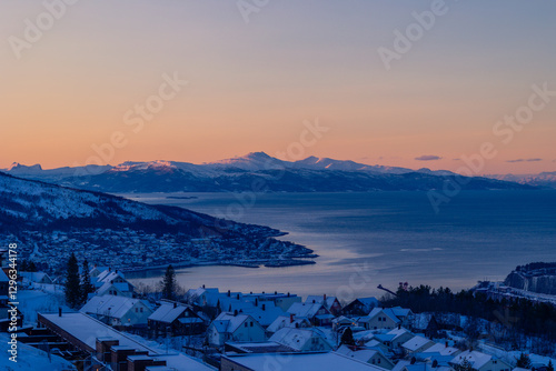 A beautiful northern city Narvik with snowy mountains over the fjord. Norway scenery of a town in arctic day. Arctic nature in Scandinavia during winter season.