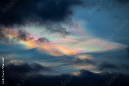 A rare polar stratospheric cloud display in the winter skies in Norway. Colorful ice crystals in the sky in sun rays. Arctic nature in Scandinavia during winter season.