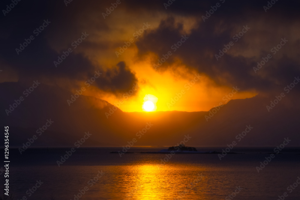 A beautiful sun shining over the snowy mountains and fjord during the first day of arctic winter. Arctic nature in Scandinavia during winter season. A beautiful sun shining over the snowy mountains and fjord during the first day of arctic winter. Arctic nature in Scandinavia during winter season.