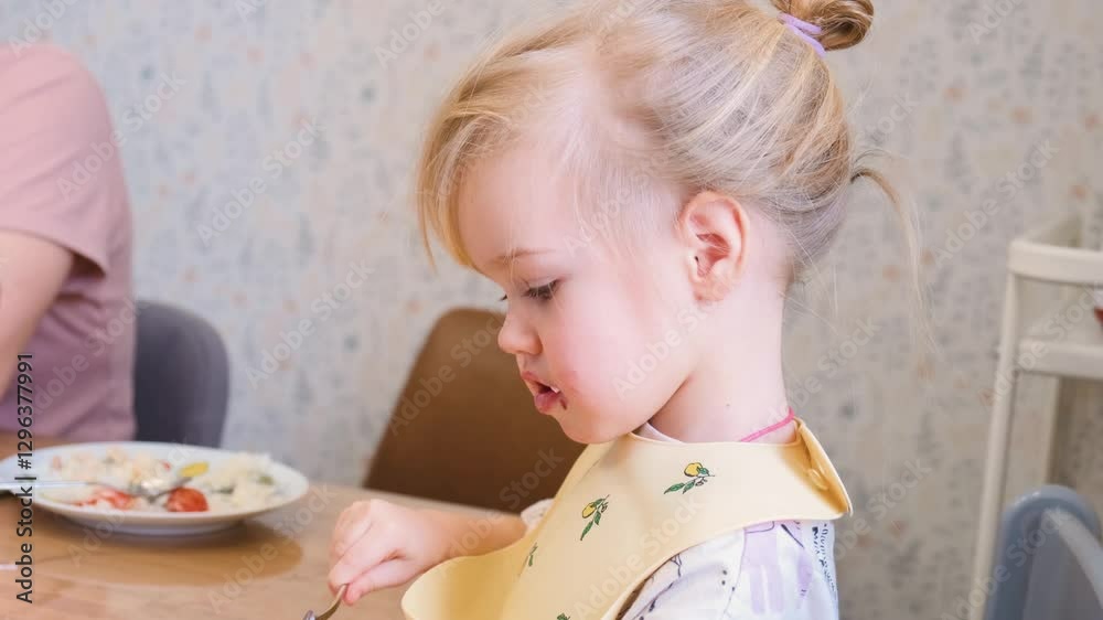 Little child girl eats by herself sitting at the kitchen table Little child girl eats by herself sitting at the kitchen table
