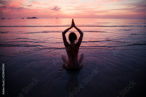 Obraz na płótnie A woman meditating on the shoreline of a subtropical beach during a beautiful sunset. w salonie