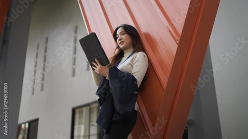 Wallpaper Mural Young professional leaning against a wall, thoughtfully working on a tablet, planning business strategies and taking notes. Torontodigital.ca